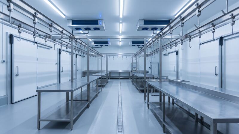Verarbeitungsraum eines Fleischbetriebs mit Deckenverdampfern, Hängebahn und Kühlraumtüren